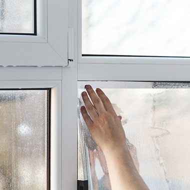 a person installing a tinted window film onto their wet windows