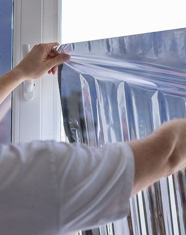 a person installing a solar protection window film on a domestic home's window