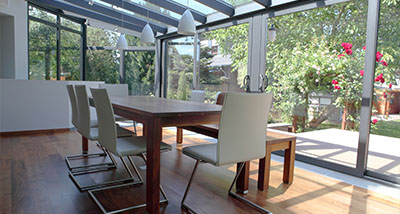 a conservatory with windows leading out to a garden, with a table and chairs within