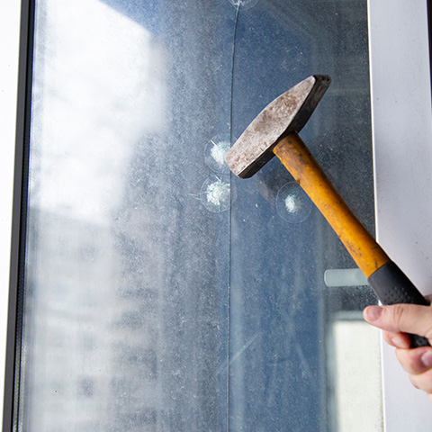 a hammer making dents on a protective window film to show how it helps prevent brake-in damage