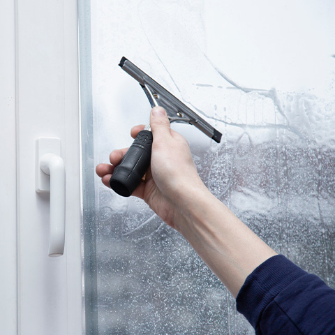 a person using a squeegee to apply a protective window film to a window