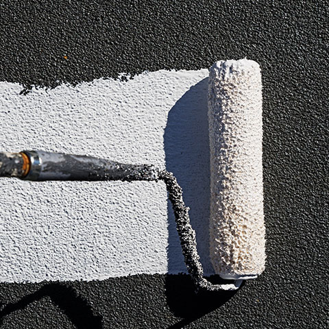 a person using a paint roller onto a black textured wall