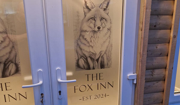 a decorative window film on a door showing an illustration of a fox and text for the Fox Inn