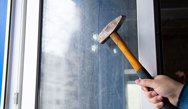 a hammer making dents on a protective window film to show how they protect windows