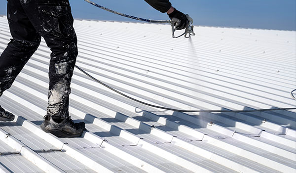 a man spraying solar reflective paint onto a aluminium roof